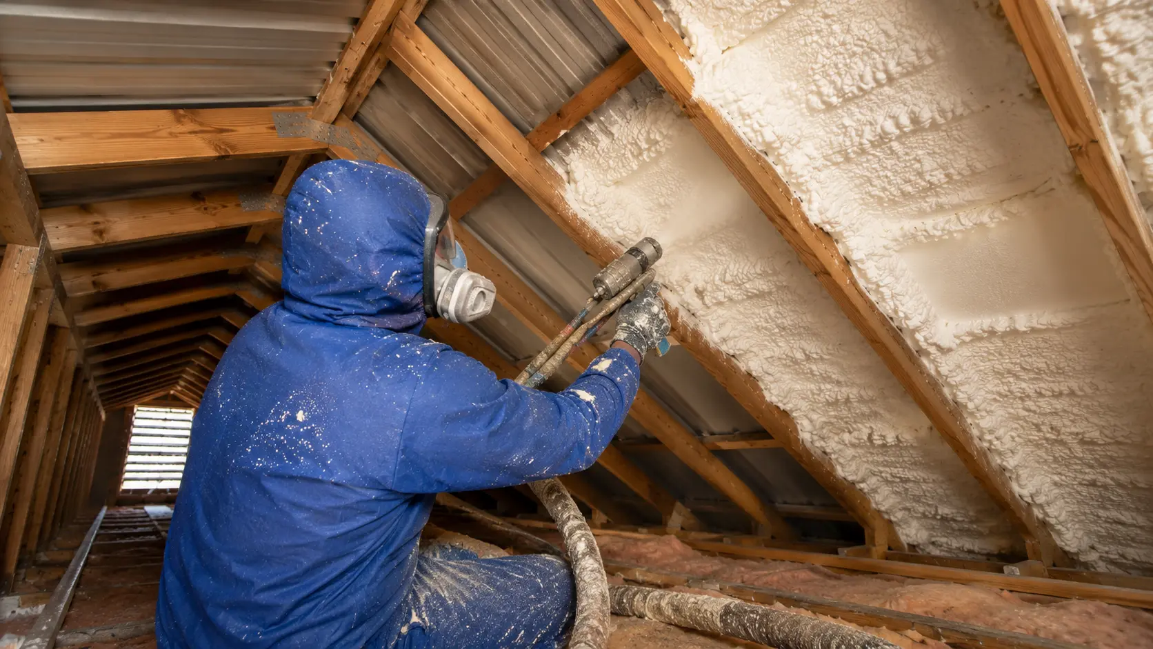 Professional installer applying spray foam inside a Brisbane roof cavity during the spray foam insulation installation process